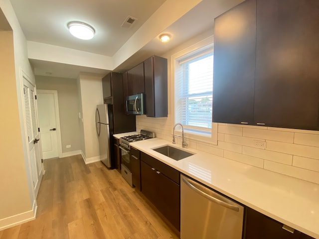 kitchen with light hardwood / wood-style flooring, stainless steel appliances, sink, decorative backsplash, and dark brown cabinetry