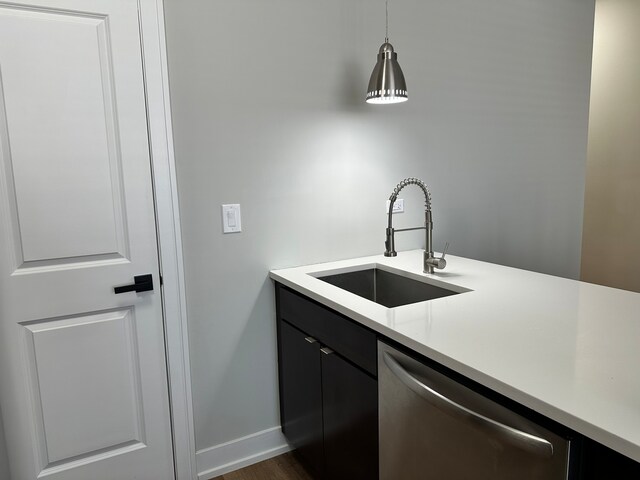 kitchen featuring dark hardwood / wood-style floors, stainless steel dishwasher, sink, and hanging light fixtures