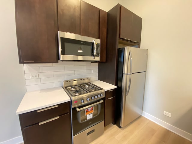 kitchen featuring light hardwood / wood-style flooring, dark brown cabinetry, appliances with stainless steel finishes, and decorative backsplash