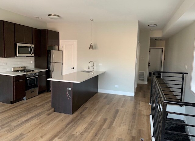 kitchen with backsplash, kitchen peninsula, appliances with stainless steel finishes, and light hardwood / wood-style floors