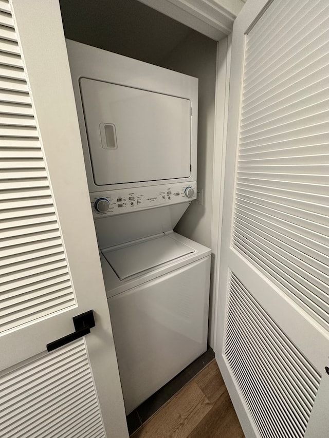 washroom with dark wood-type flooring and stacked washer and dryer