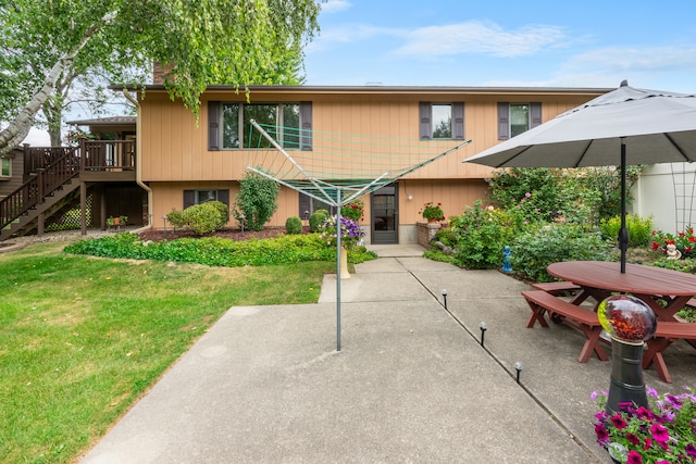 view of front of house with a wooden deck, a patio, and a front lawn