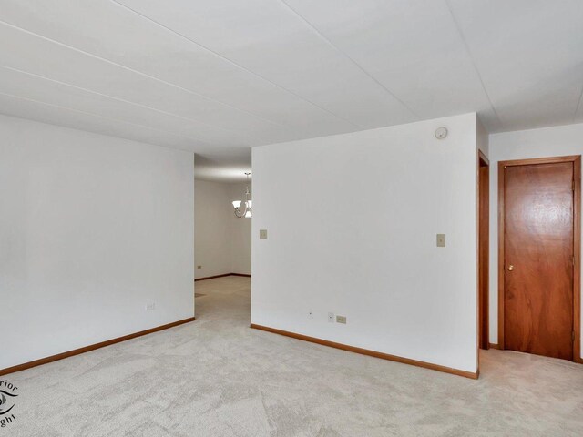 carpeted spare room featuring a chandelier