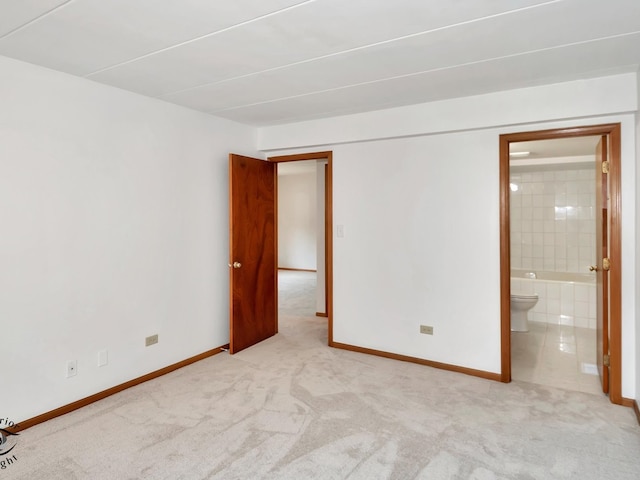 unfurnished bedroom featuring light colored carpet and ensuite bathroom