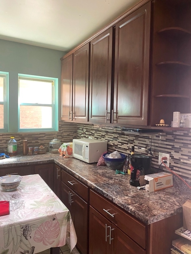 kitchen with decorative backsplash, dark brown cabinetry, and dark stone countertops