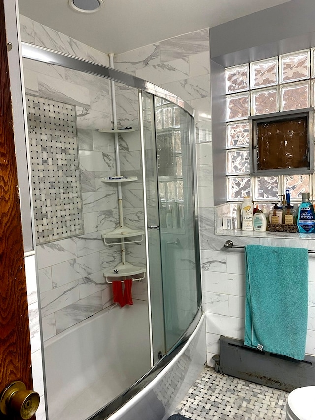 bathroom featuring toilet, tile walls, tile patterned floors, and shower / bath combination with glass door