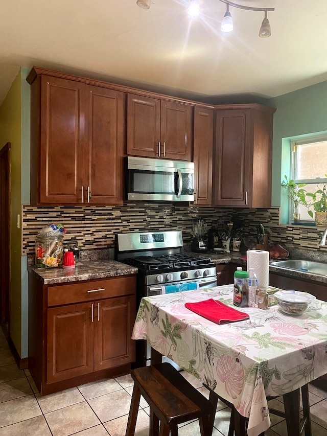 kitchen with sink, stainless steel appliances, backsplash, and light tile patterned floors