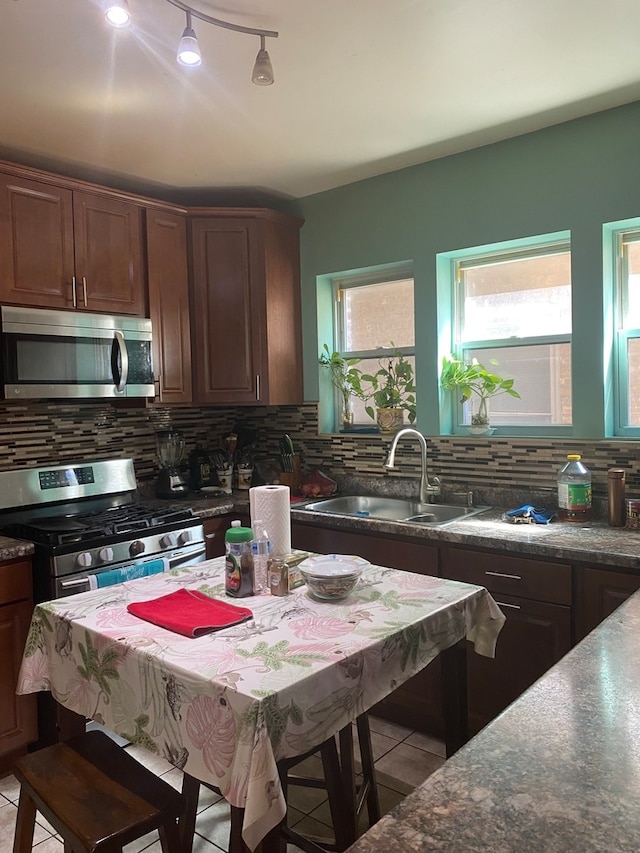 kitchen featuring sink, decorative backsplash, stainless steel appliances, and light tile patterned floors