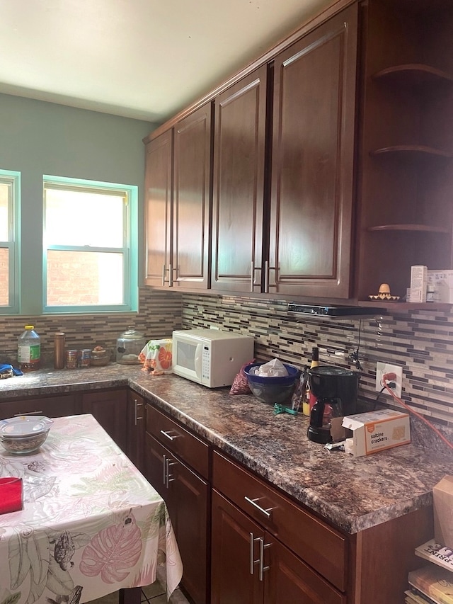 kitchen featuring dark brown cabinets, dark stone counters, and decorative backsplash