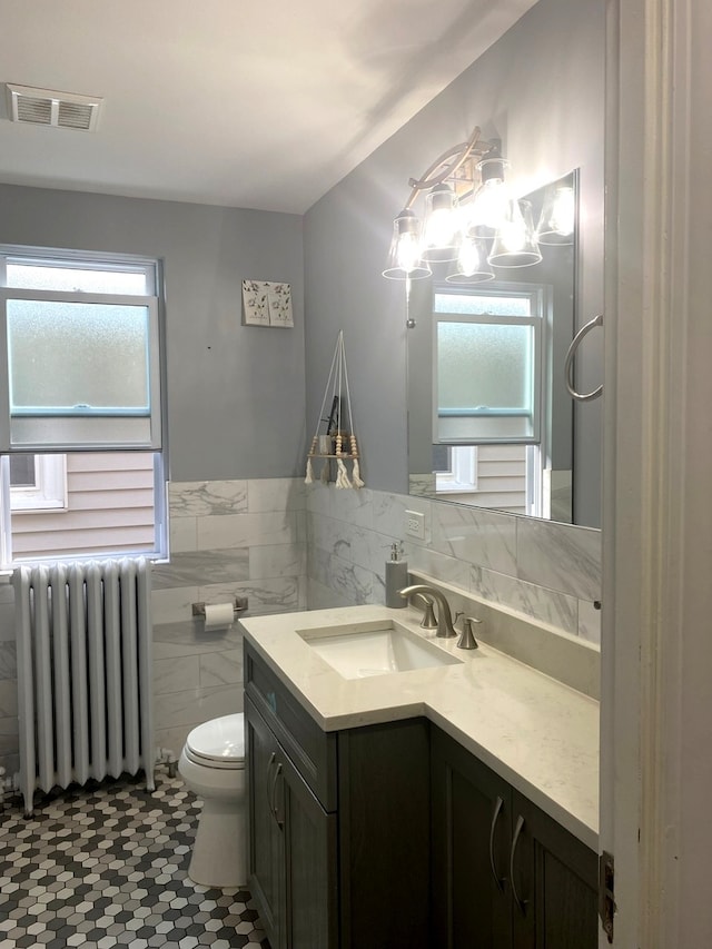 bathroom featuring radiator, toilet, plenty of natural light, and vanity