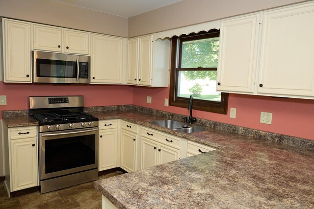 kitchen featuring stainless steel appliances, dark countertops, and a sink