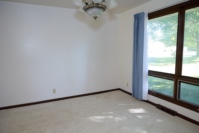 empty room with baseboards, visible vents, and light colored carpet