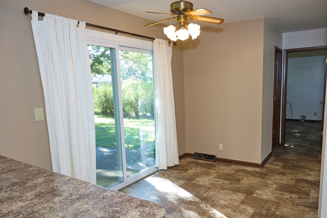 interior space with stone finish floor, baseboards, visible vents, and a ceiling fan