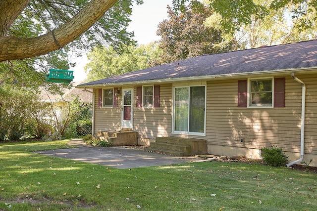 rear view of house with a shingled roof, entry steps, and a yard