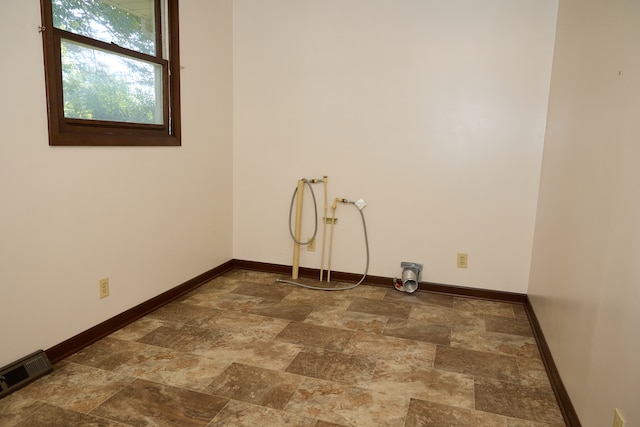 empty room with stone finish floor, visible vents, and baseboards