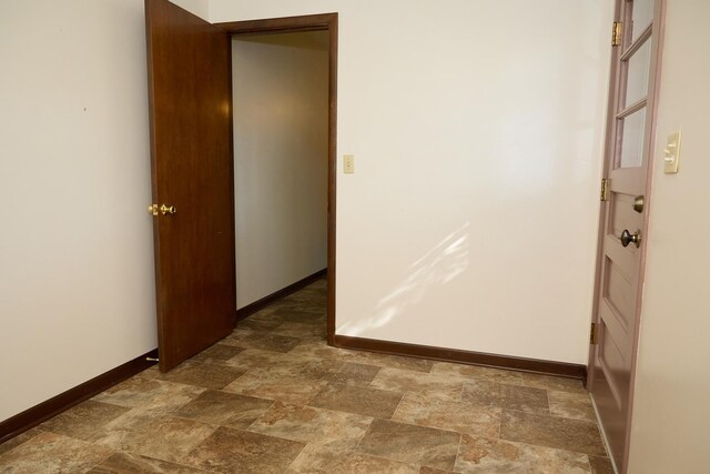 hallway with stone finish floor and baseboards