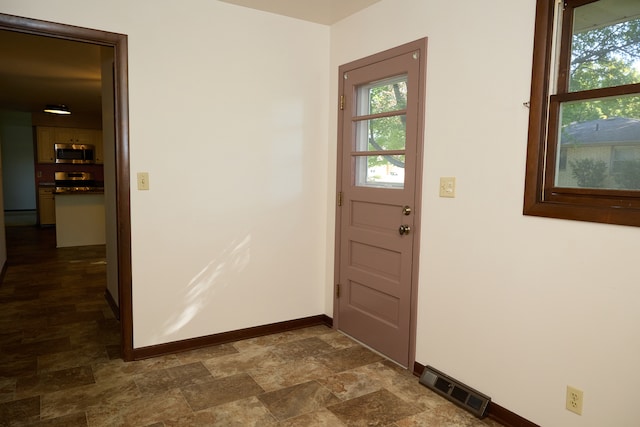 doorway featuring stone finish floor, baseboards, and visible vents