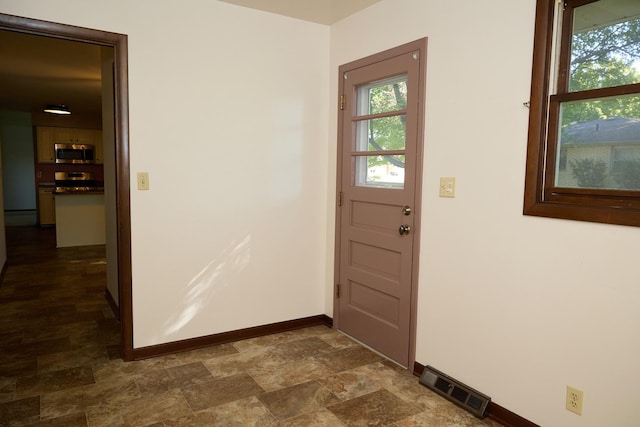 doorway to outside with baseboards, visible vents, and stone finish flooring