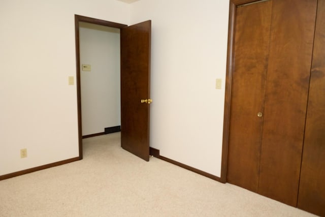 unfurnished bedroom with light colored carpet, baseboards, and a closet