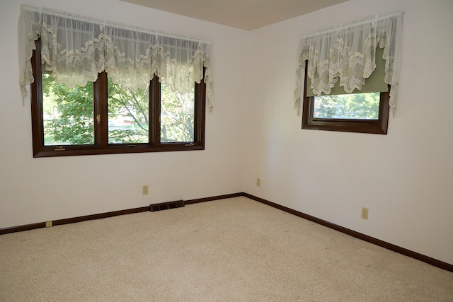 carpeted spare room with visible vents and baseboards