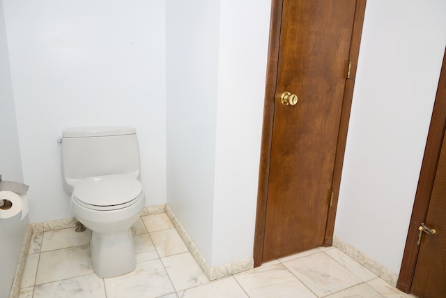 bathroom with marble finish floor, baseboards, and toilet