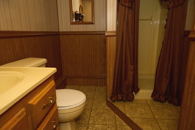 full bathroom featuring curtained shower, toilet, vanity, wainscoting, and wallpapered walls