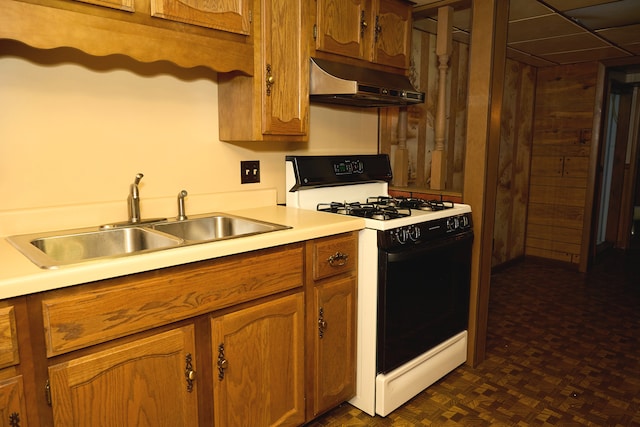 kitchen featuring range with gas stovetop, brown cabinets, light countertops, under cabinet range hood, and a sink