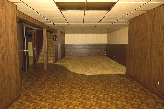 below grade area featuring a paneled ceiling and wooden walls