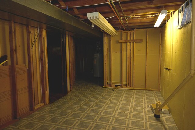 unfinished basement with water heater and tile patterned floors