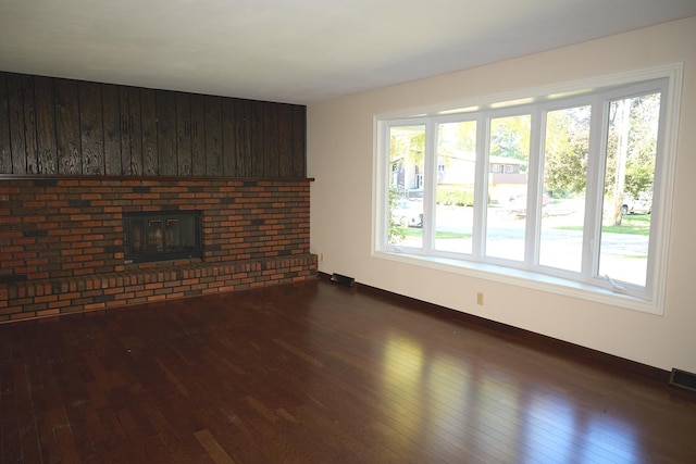unfurnished living room with visible vents, a fireplace, and dark wood-style flooring