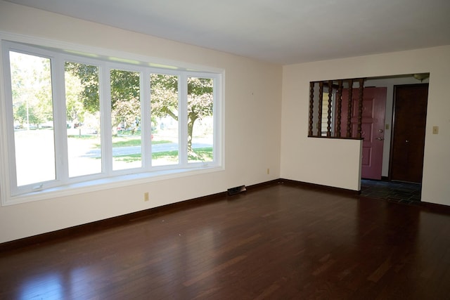 empty room with dark wood-type flooring and baseboards
