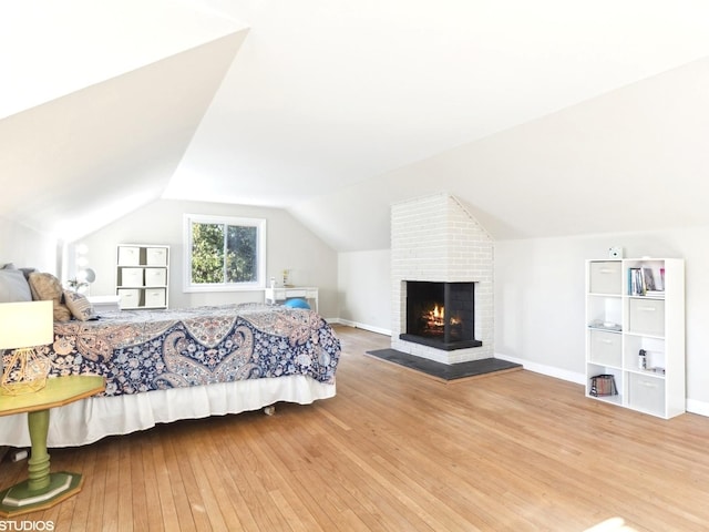 bedroom featuring a fireplace, wood-type flooring, and lofted ceiling