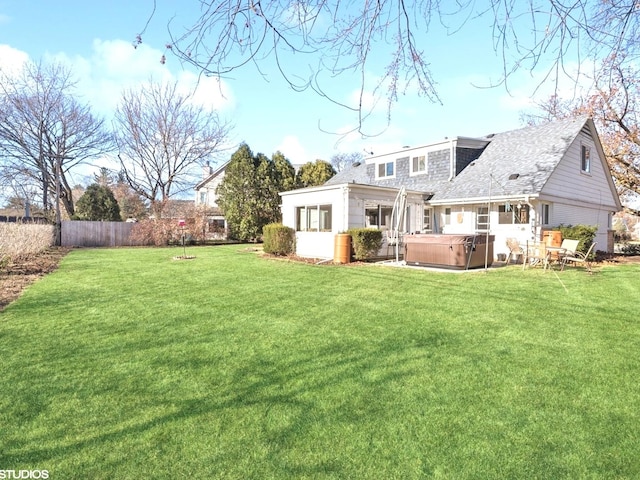 rear view of property with a yard and a hot tub