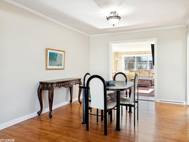 dining area with hardwood / wood-style flooring and ornamental molding