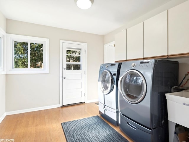 laundry area featuring sink, washer and clothes dryer, cabinets, and light wood-type flooring