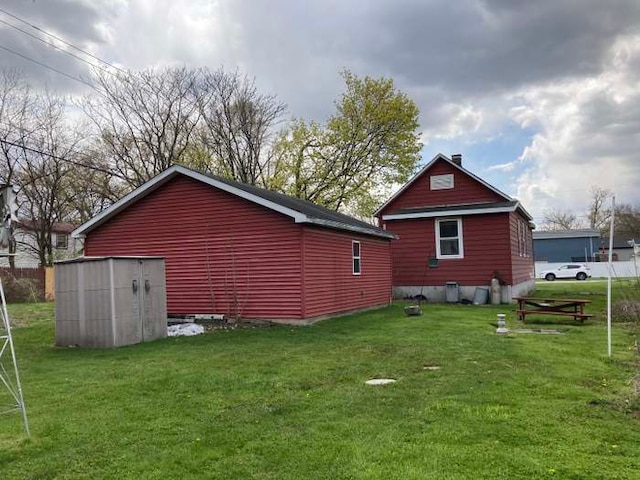 rear view of property with a lawn and an outdoor structure