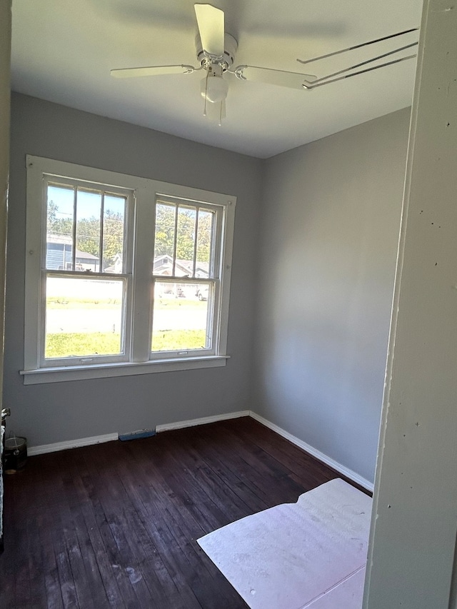 empty room with plenty of natural light, ceiling fan, and dark hardwood / wood-style flooring