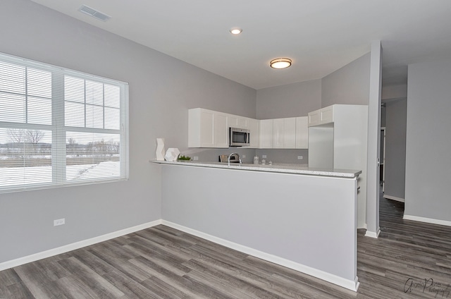 kitchen with white cabinets, dark hardwood / wood-style floors, kitchen peninsula, and sink