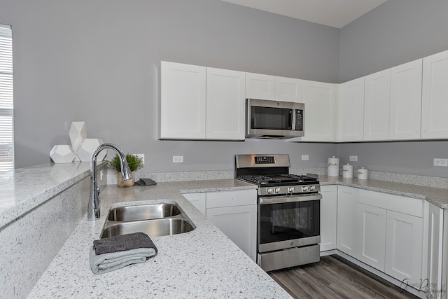 kitchen with stainless steel appliances, sink, light stone countertops, dark wood-type flooring, and white cabinets