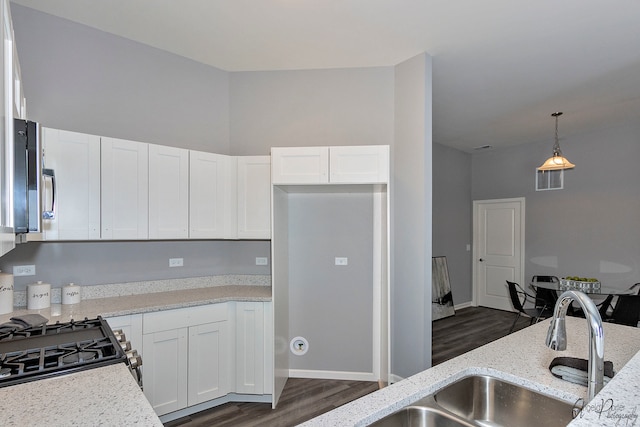 kitchen with dark wood-type flooring, white cabinets, pendant lighting, and light stone countertops