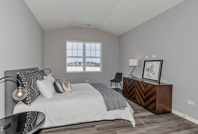 bedroom with lofted ceiling, a water view, and light hardwood / wood-style floors