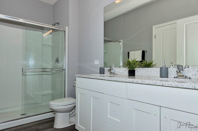 bathroom featuring vanity, toilet, hardwood / wood-style floors, and a shower with shower door