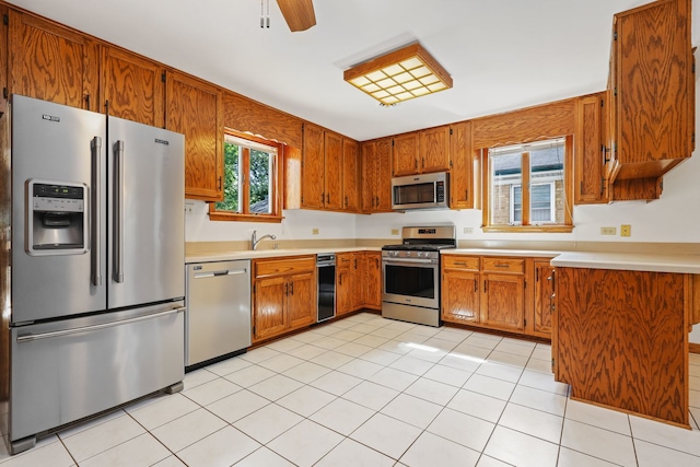 kitchen featuring appliances with stainless steel finishes, light tile patterned floors, sink, and ceiling fan