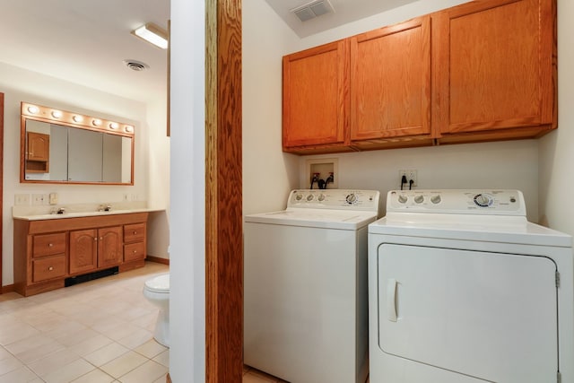 clothes washing area featuring washing machine and clothes dryer, cabinets, and light tile patterned flooring