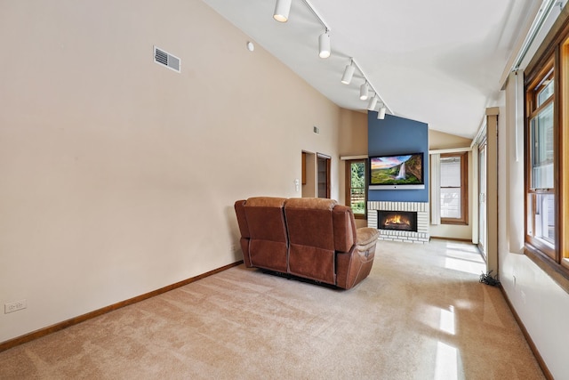 carpeted living room with rail lighting, high vaulted ceiling, and a fireplace