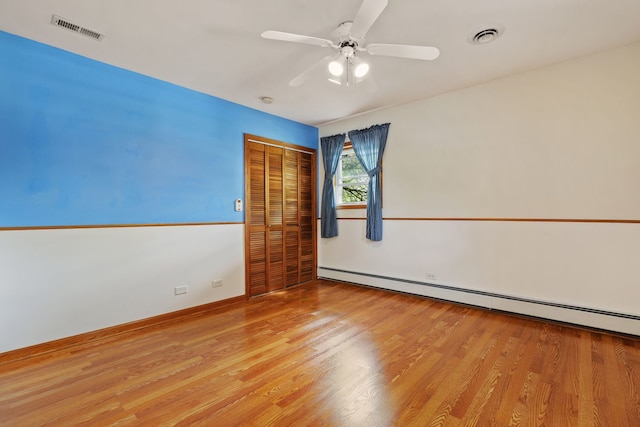 spare room with ceiling fan, baseboard heating, and light hardwood / wood-style flooring