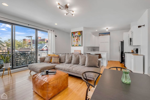 living room featuring a notable chandelier, light wood-type flooring, and sink