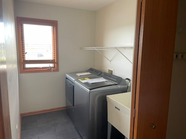 clothes washing area featuring dark tile patterned floors, independent washer and dryer, and sink