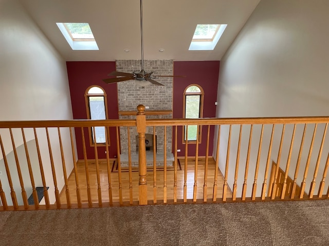 stairway with ceiling fan, carpet floors, and lofted ceiling with skylight