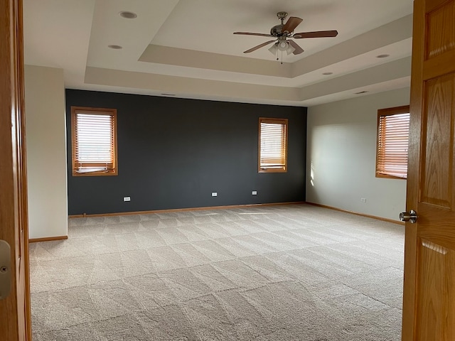 carpeted spare room with ceiling fan and a tray ceiling